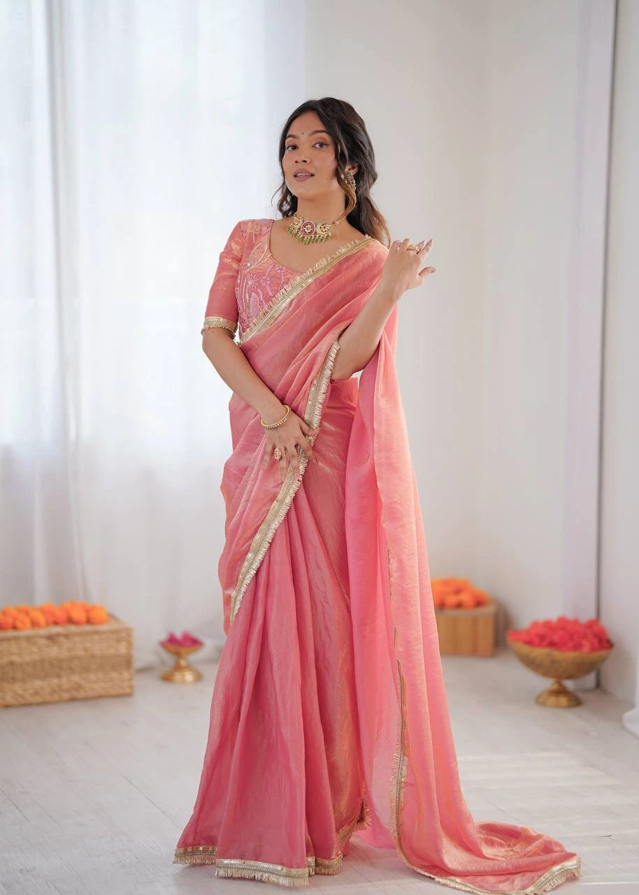 Woman wearing a pink saree with gold border in a minimalistic setting